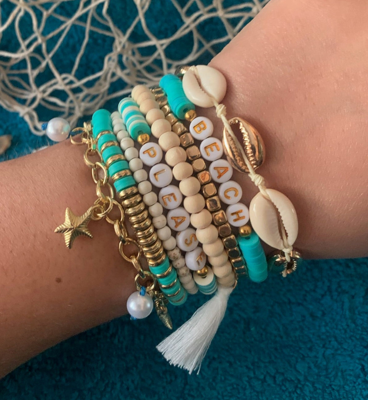 Wrist with multiple bracelets on a textured blue background