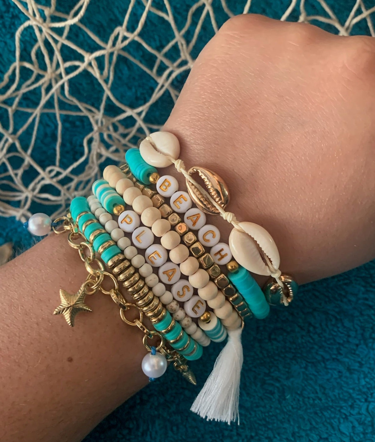 Wrist with multiple bracelets on a textured blue background