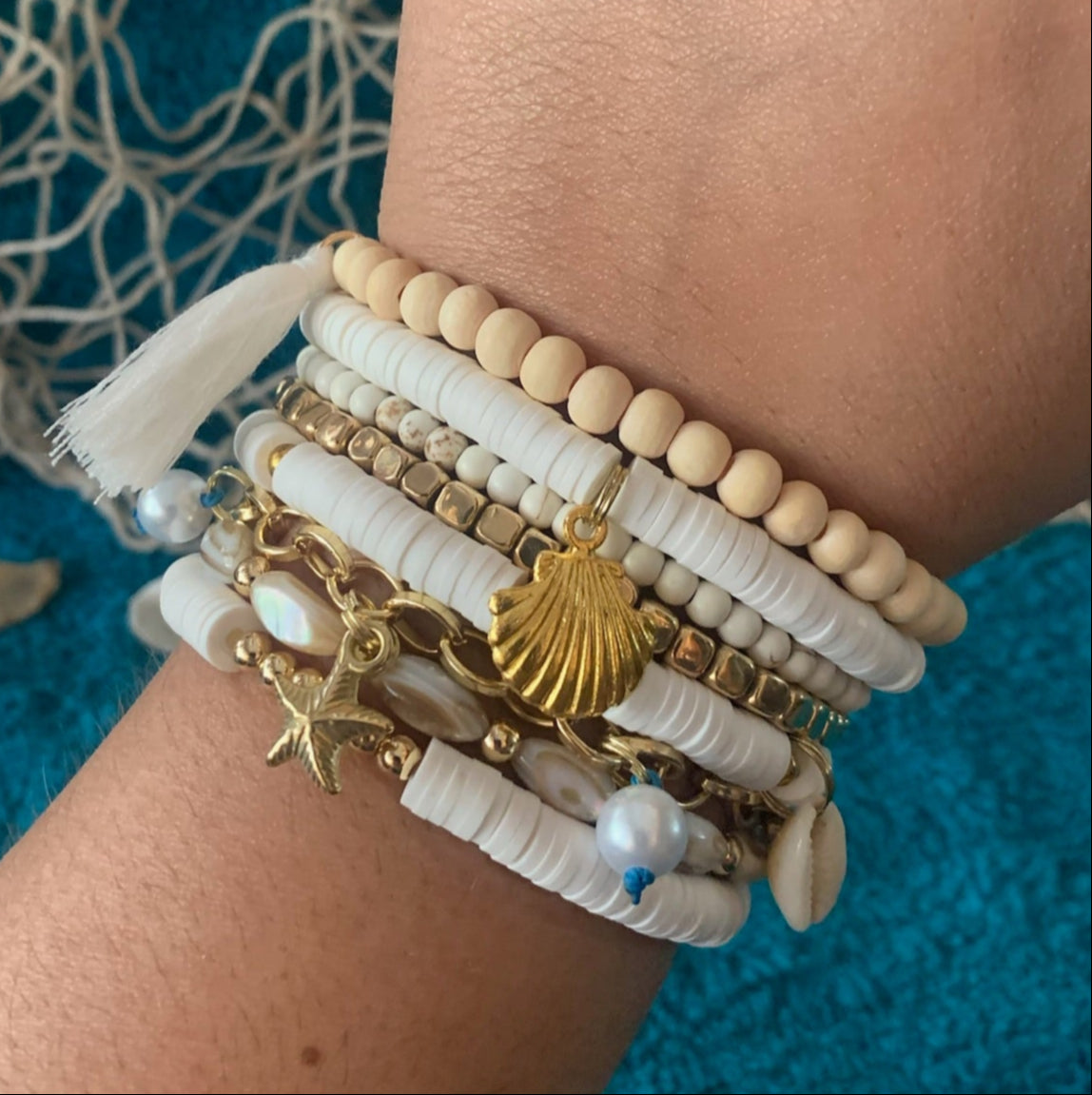Wrist wearing multiple bracelets with a blue textured background