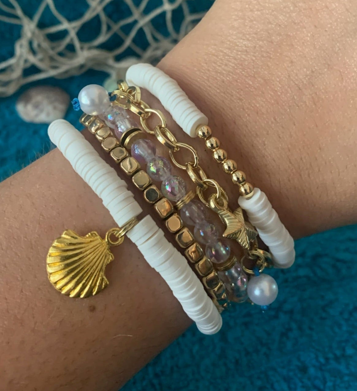 Wrist wearing multiple bracelets with a blue textured background