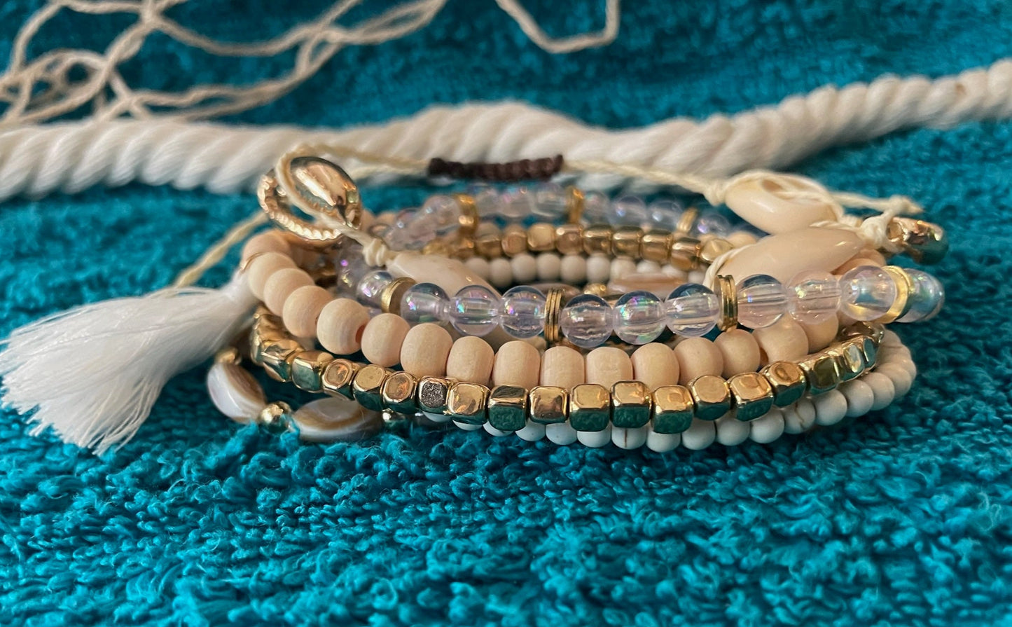 Stack of beaded bracelets with tassel on a textured blue surface