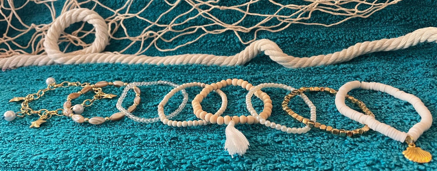 Jewelry set including bracelets and necklaces on a textured blue surface with fishing net in the background.