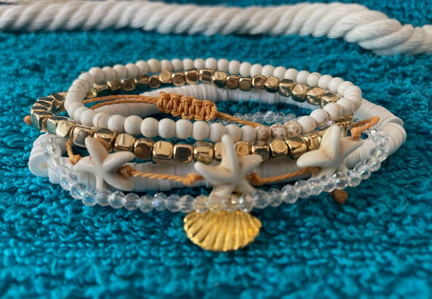 Set of beaded bracelets with starfish and shell charms on a textured blue surface