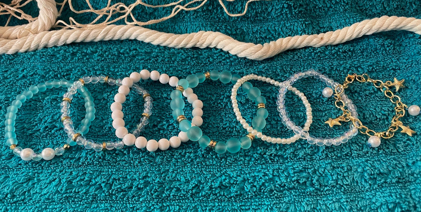 Set of beaded bracelets on a textured teal surface with fishing net and rope.