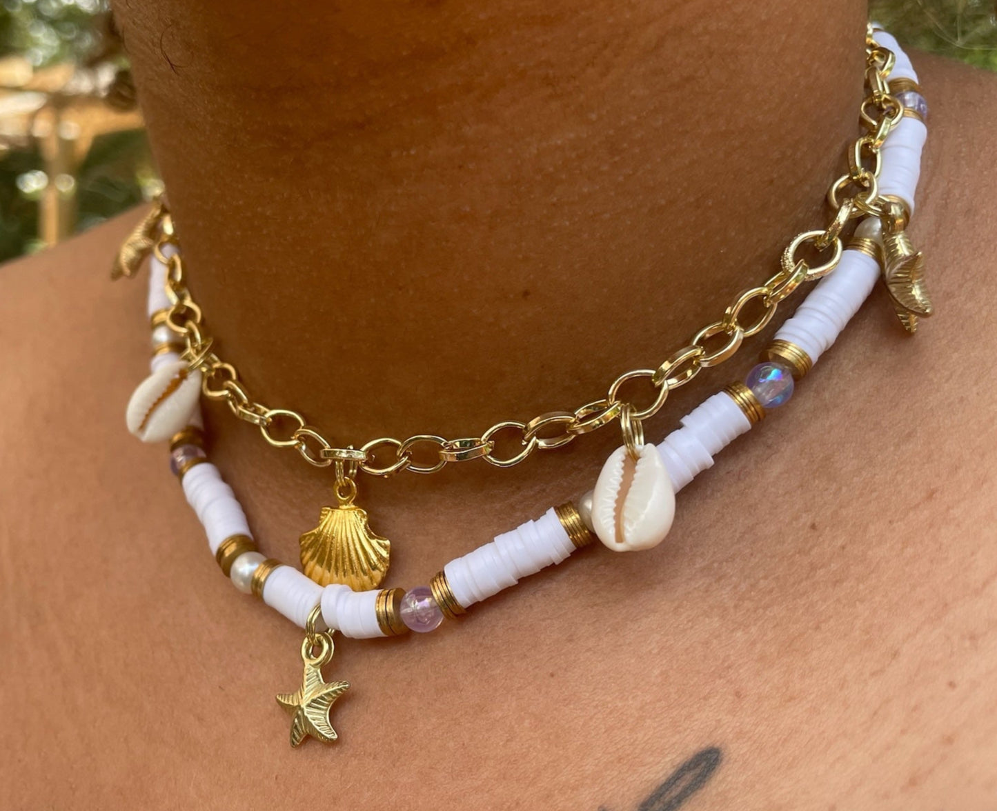 Necklace with shell and star charms on a person's neck