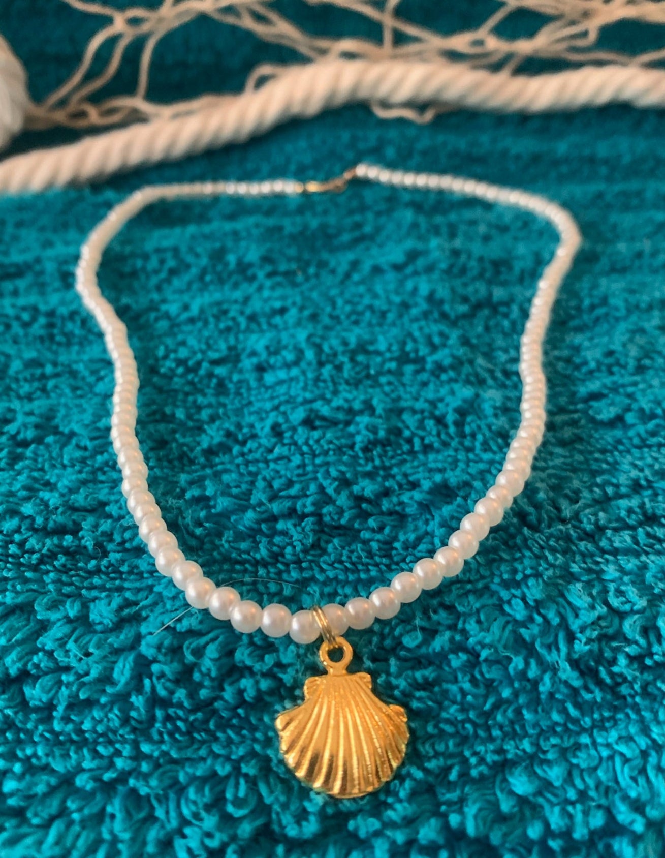 Necklace with a gold shell pendant on a textured blue surface
