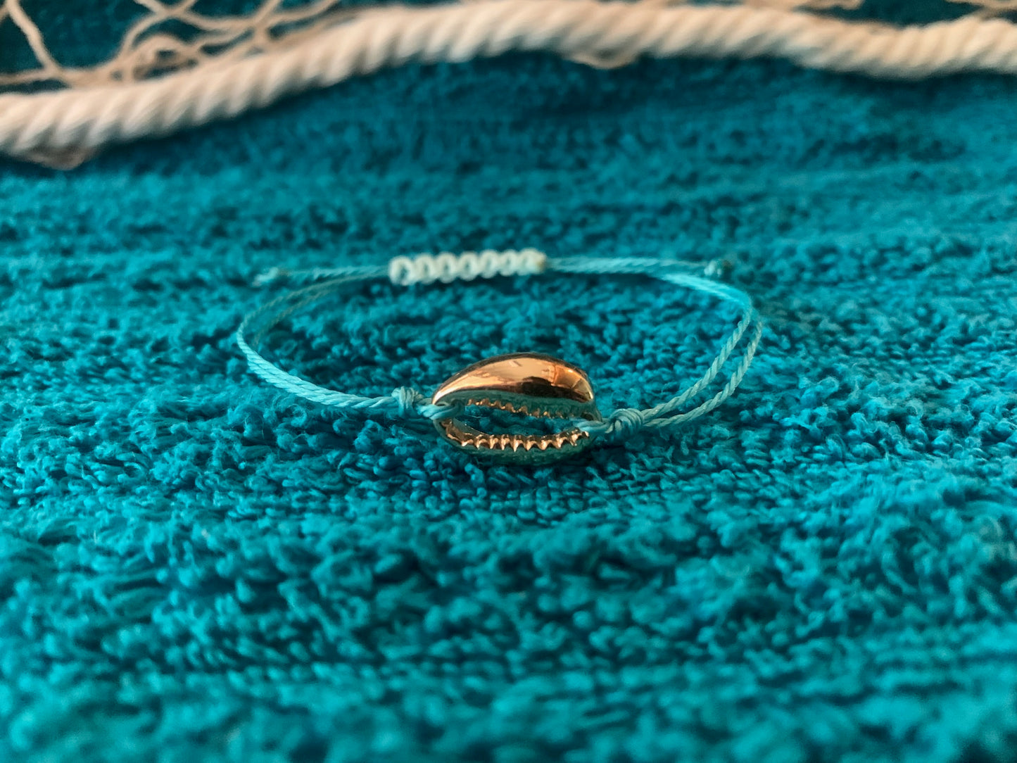 Bracelet with a shell charm on a textured blue surface