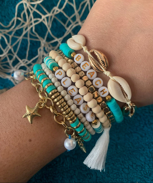 Multistrand bracelet with beads and charms on a wrist against a textured blue background