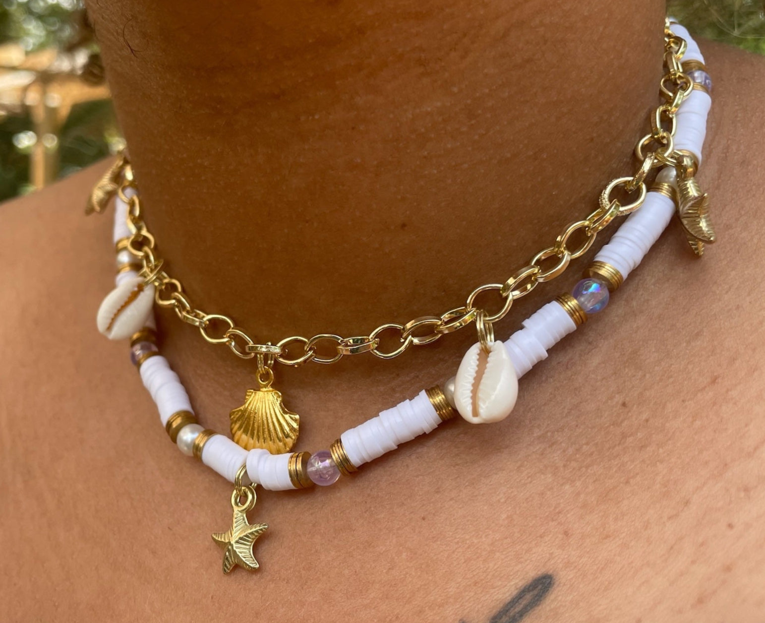 Necklace with shell and star charms on a person's neck