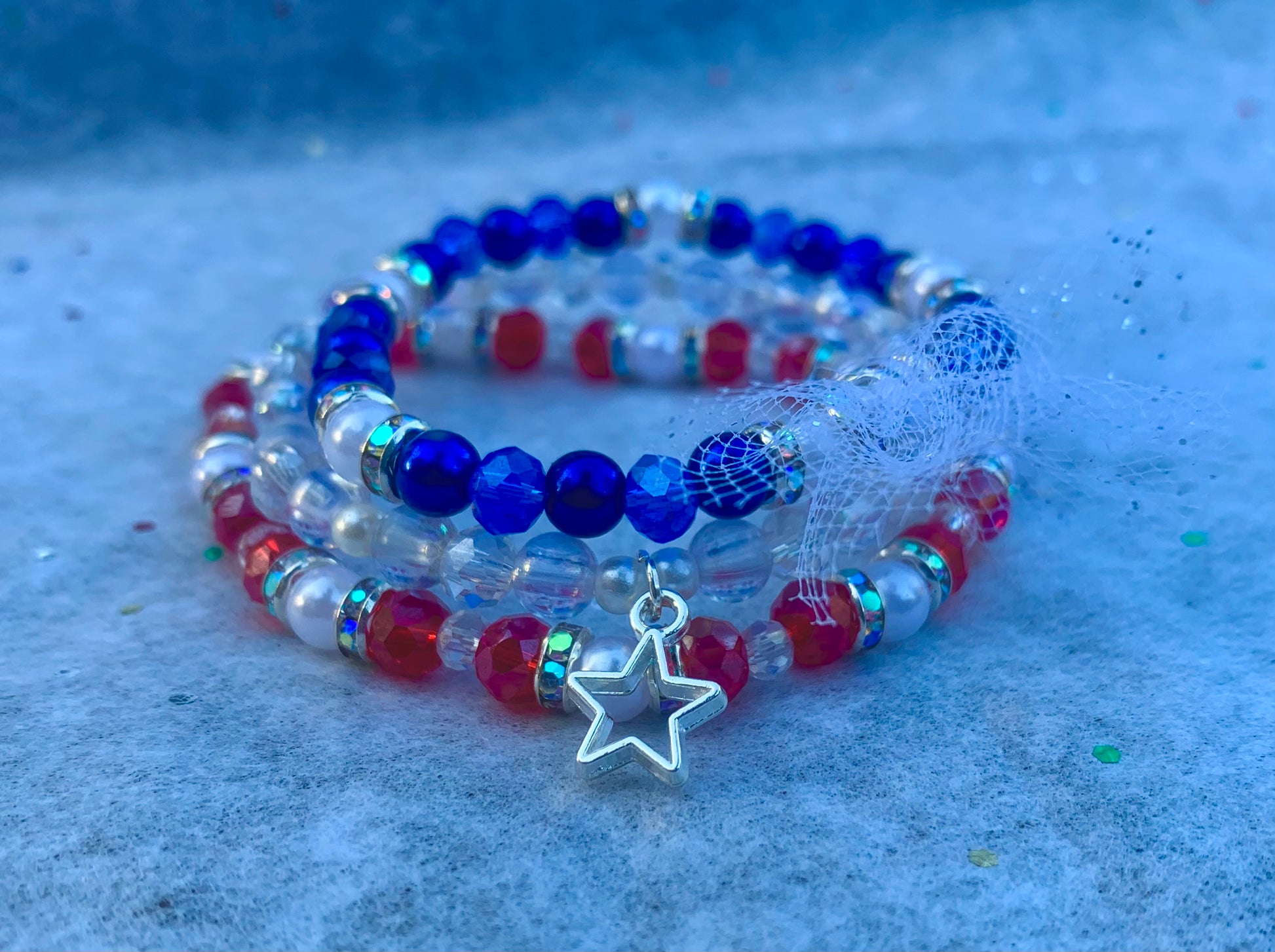 Beaded bracelets with star charm on a textured blue surface