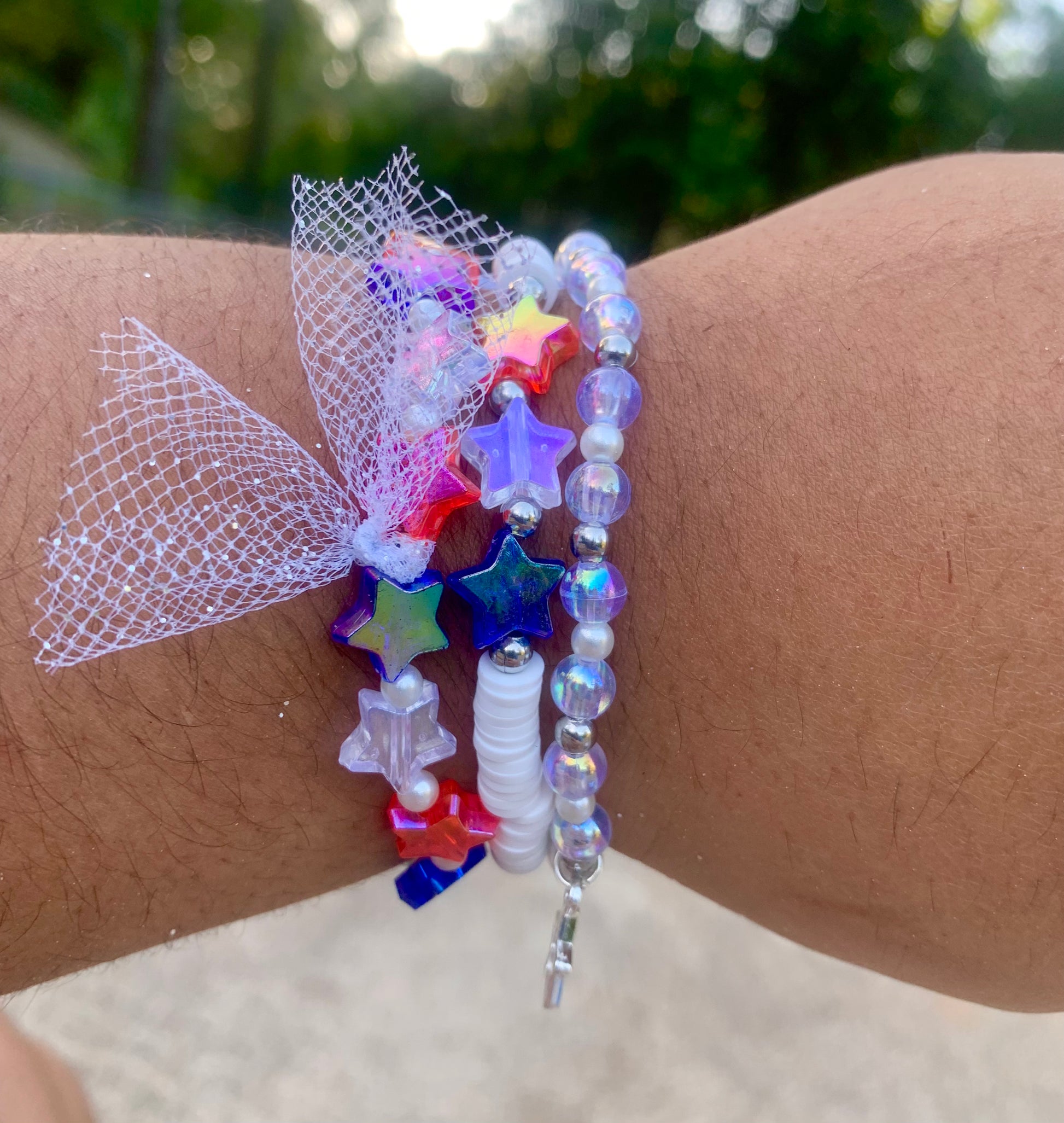 Colorful beaded bracelet with star-shaped beads on a wrist against a blurred natural background