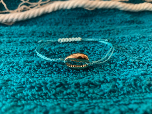 Bracelet with a shell charm on a textured blue surface
