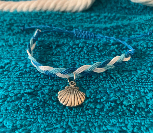 Bracelet with a shell charm on a blue textured surface