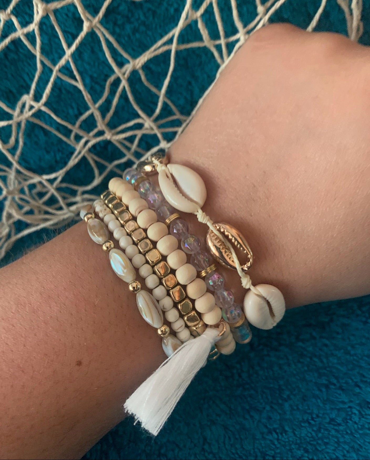 Close-up of a wrist wearing multiple beaded bracelets on a textured blue background